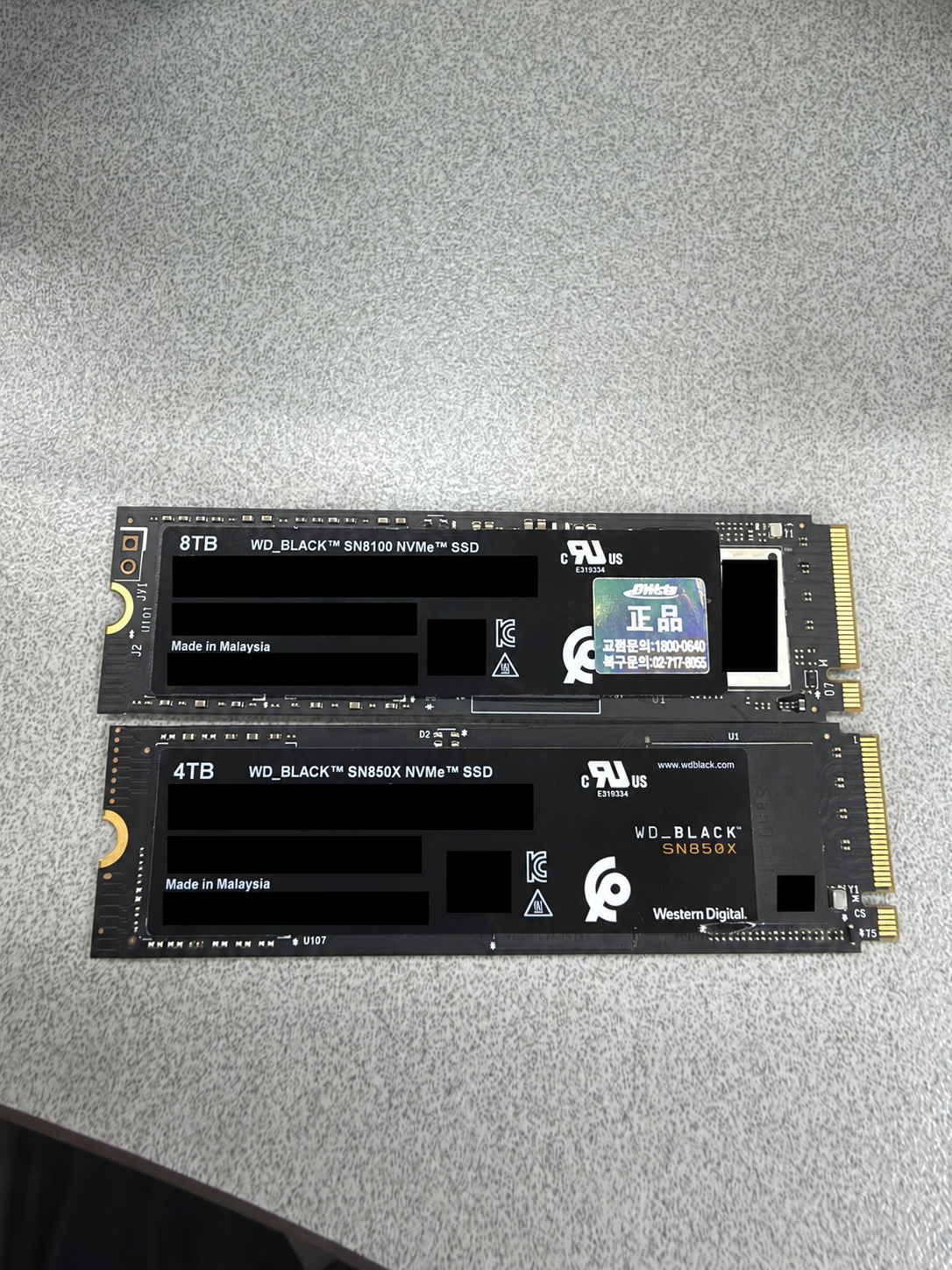 위쪽 WD_BLACK SN8100 8TB와 아래쪽 SN850X 4TB SSD의 크기와 라벨 비교, 제품 식별자는 가림 처리
